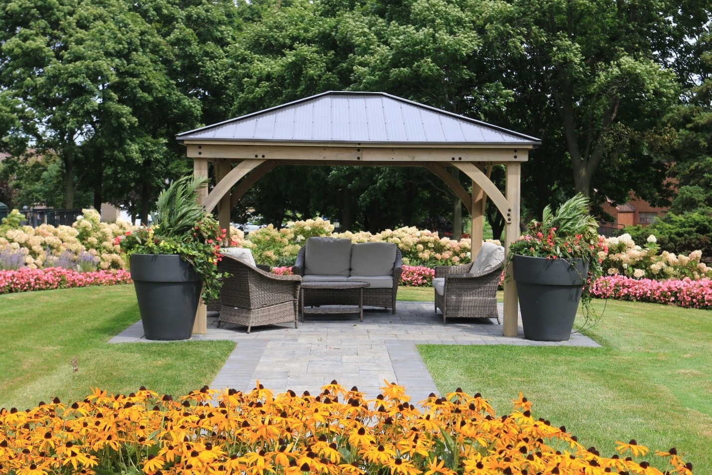 A garden scene features a gazebo with seating, surrounded by colorful flowers and lush trees, creating a serene and inviting atmosphere.